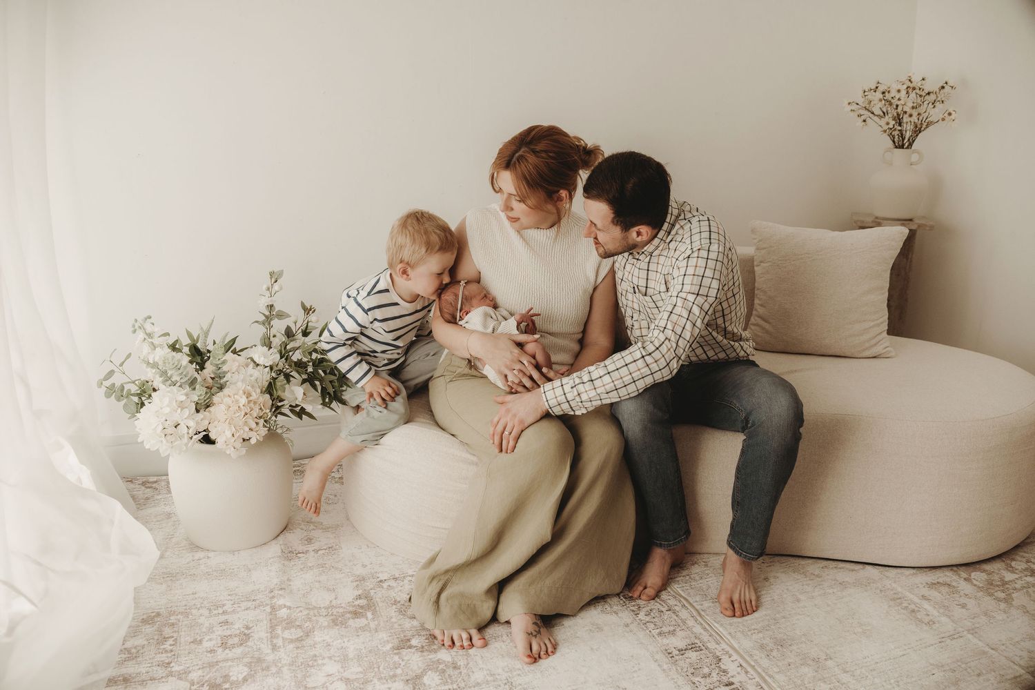 Mum and child sitting together on a sofa during a relaxed family photography session.