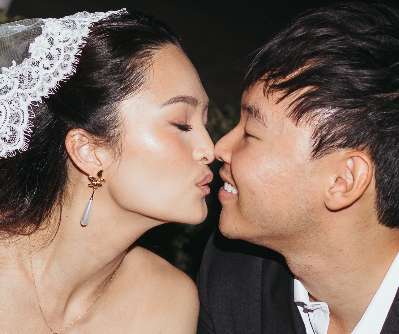 Bride and groom share a tender kiss closeup with bride wearing a delicate lace headpiece.