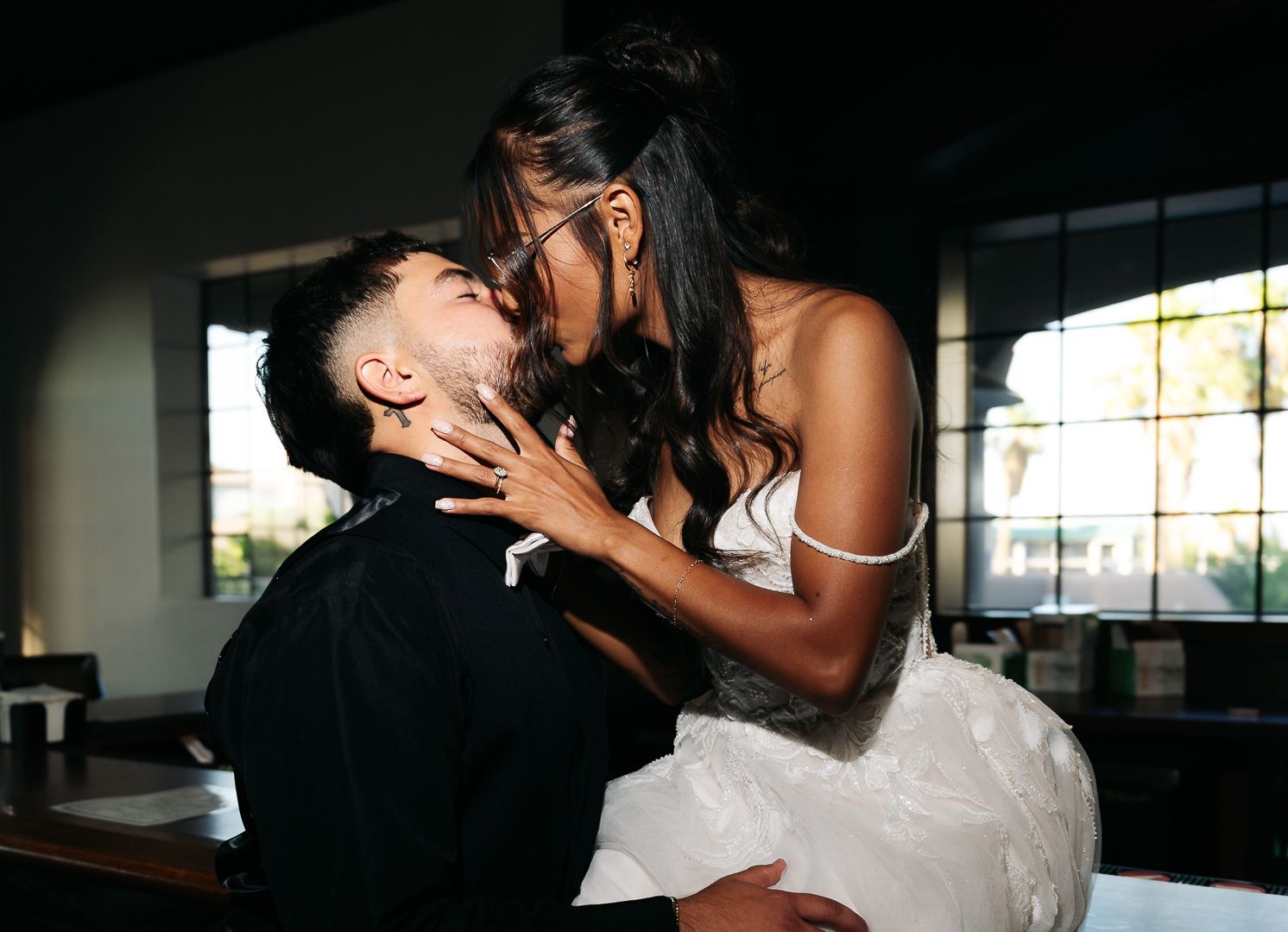 A bride and groom share a passionate kiss, with the bride in a white dress holding the groom's face tenderly.