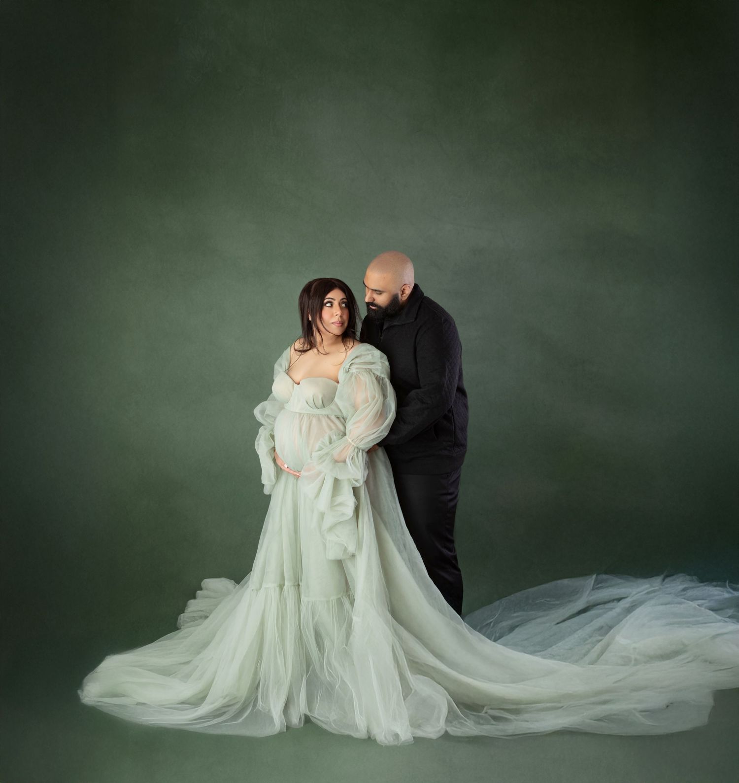 Maternity couple portrait with woman in mint tulle gown and man in black outfit.