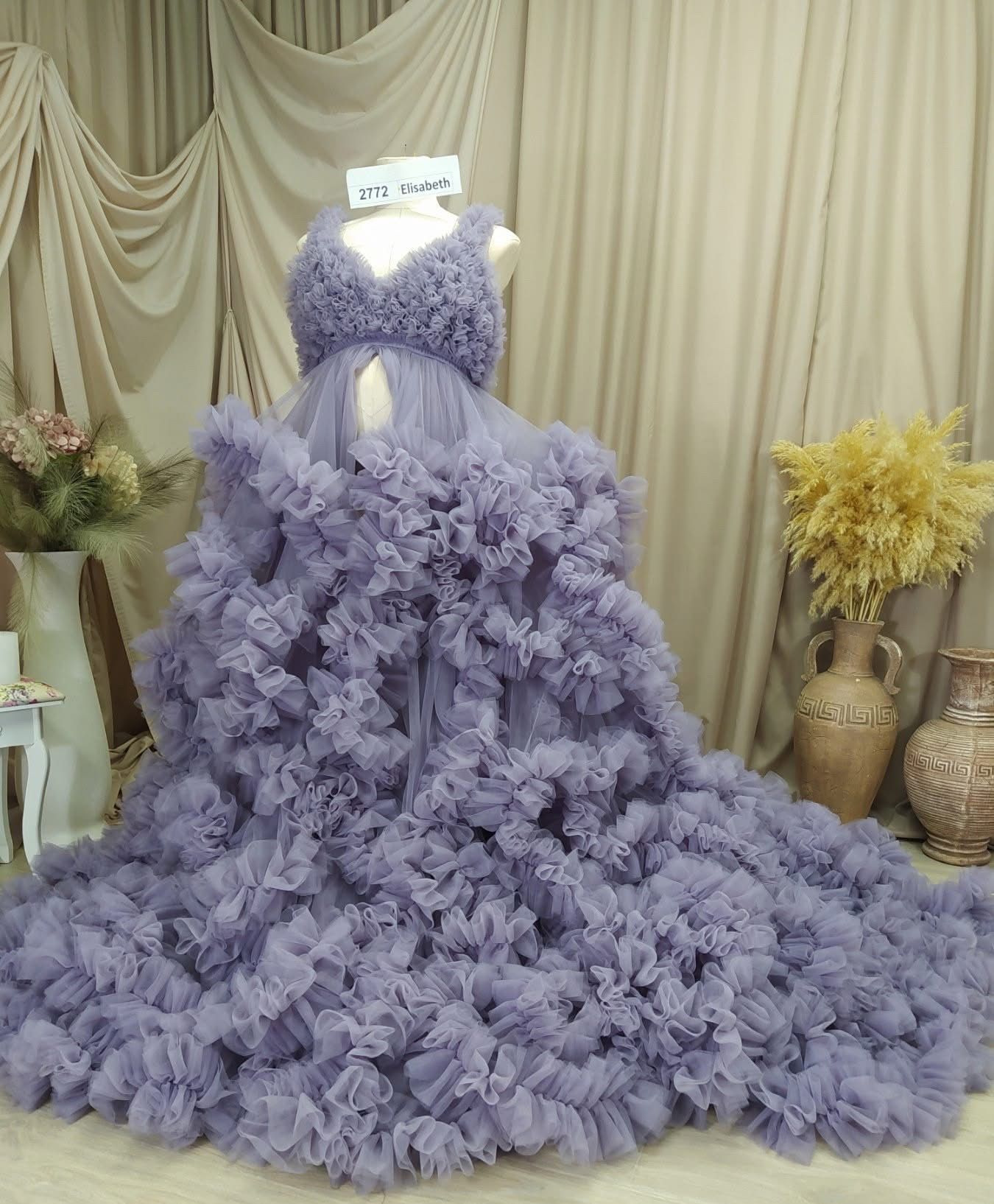 Lavender purple ruffled tulle maternity gown with open front and cascading floral train on mannequin.
