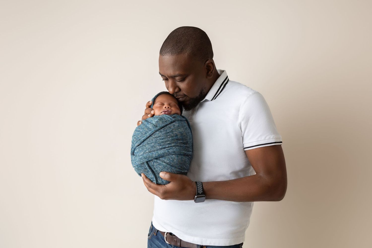 Father tenderly holding his swaddled newborn baby close to his chest.