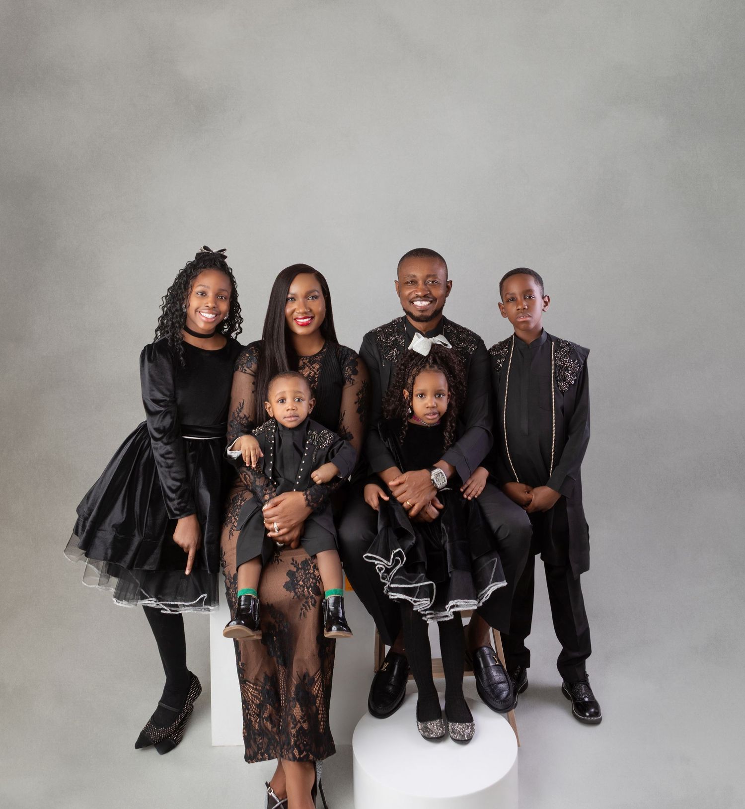 Family of six dressed in coordinated black outfits posing together in professional studio portrait.