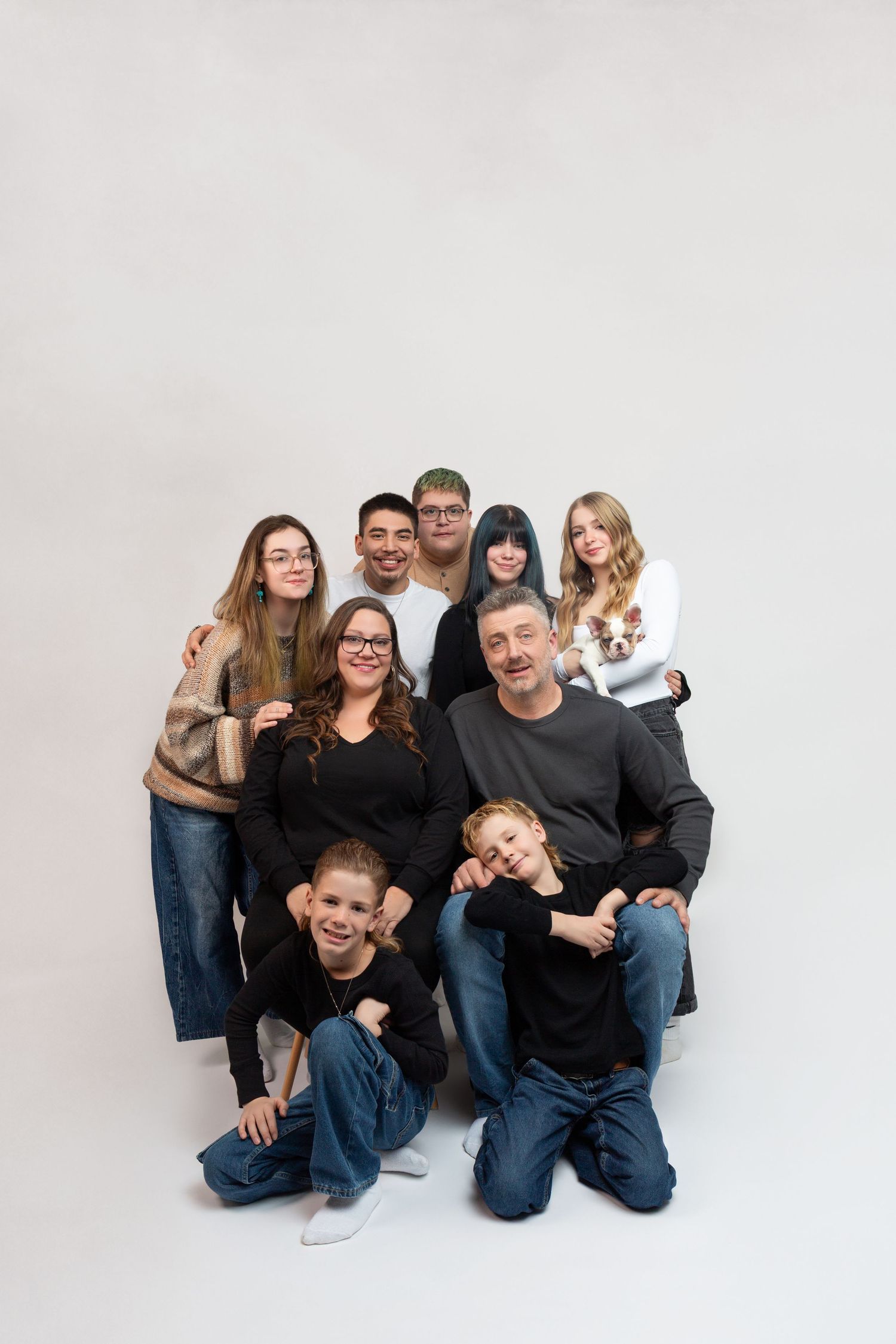 Large family group portrait with eight members posing together on white background.