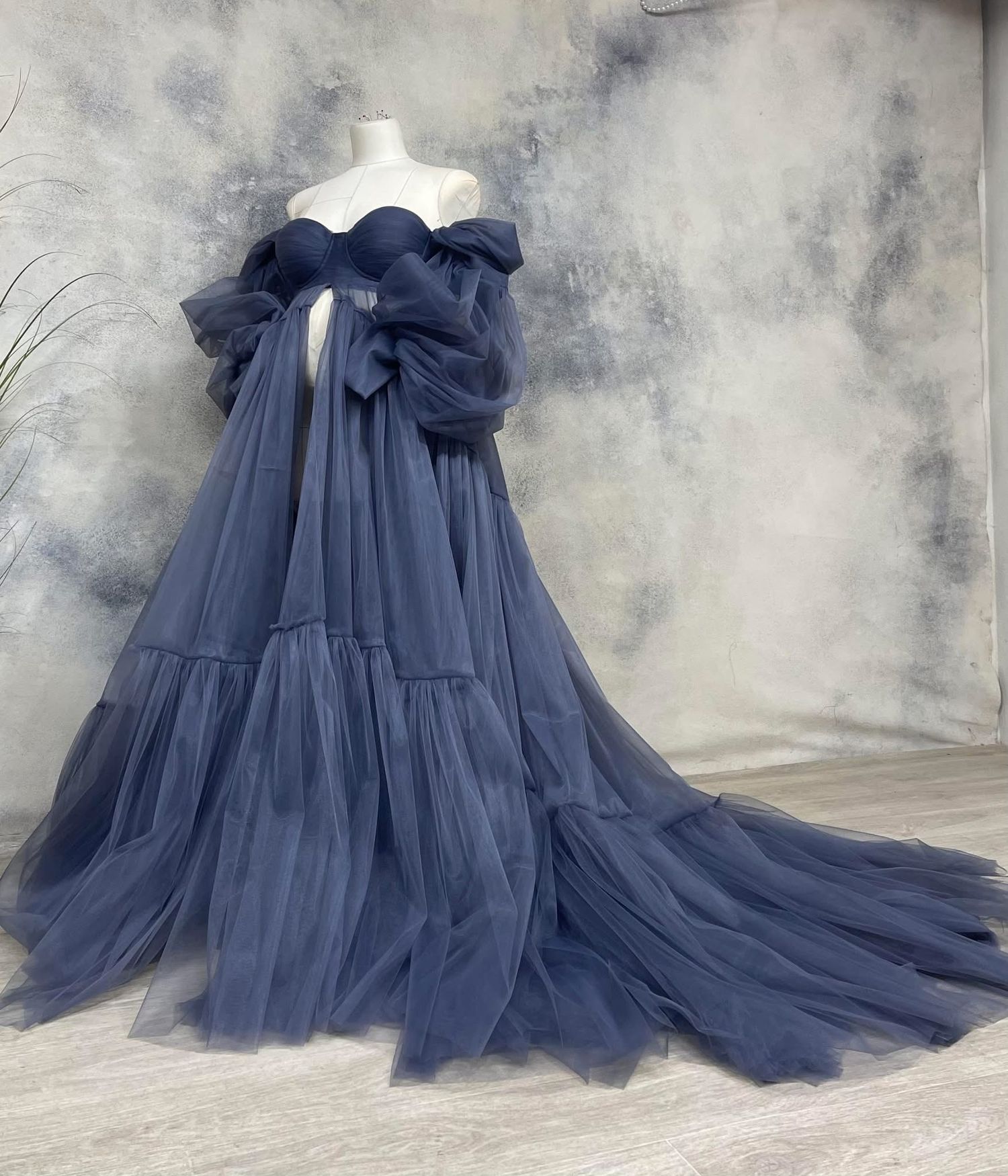 Dusty navy off-shoulder tiered tulle maternity gown on a mannequin.