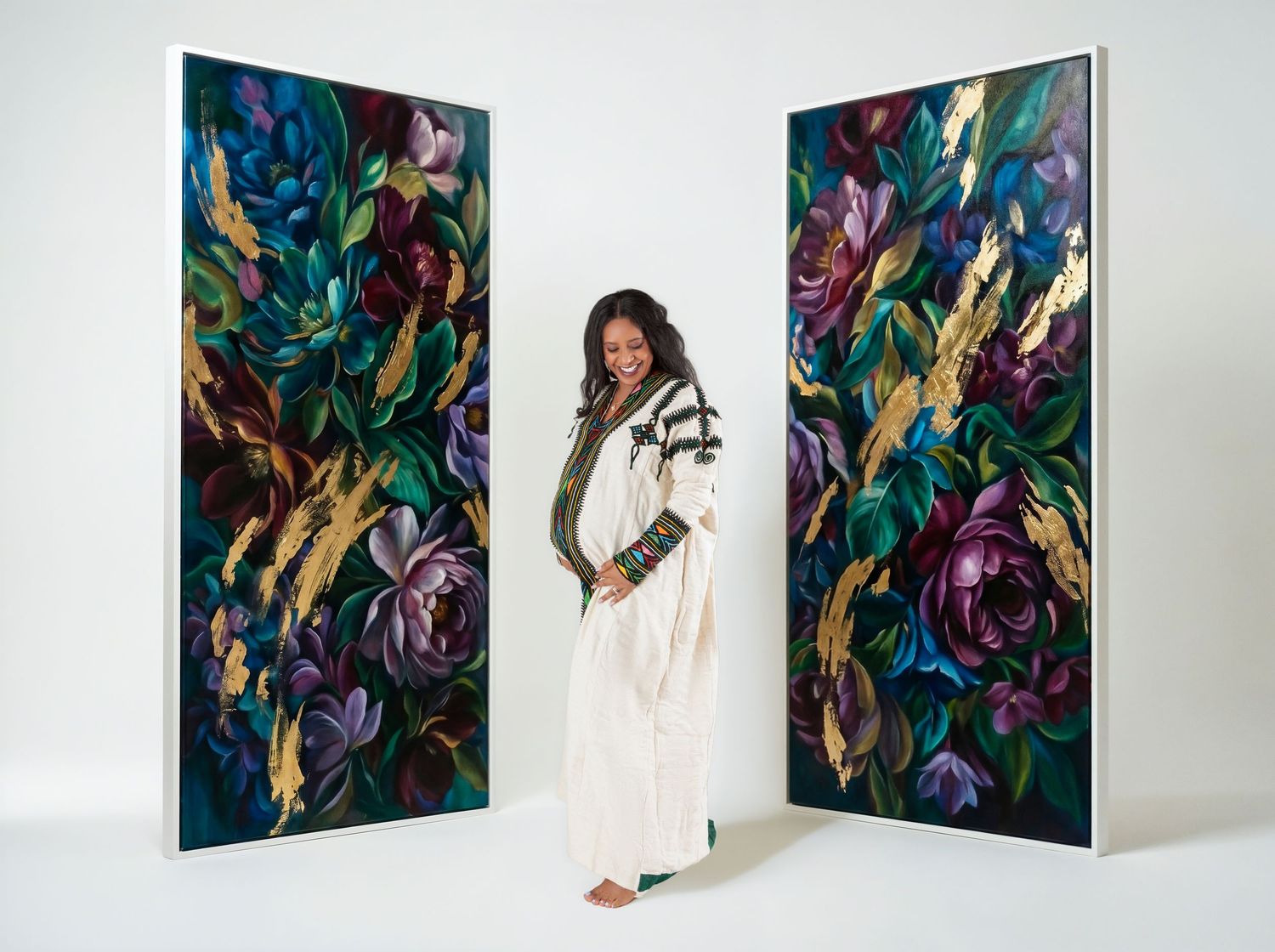 Woman in white dress stands between two large floral paintings with purple roses and gold accents.