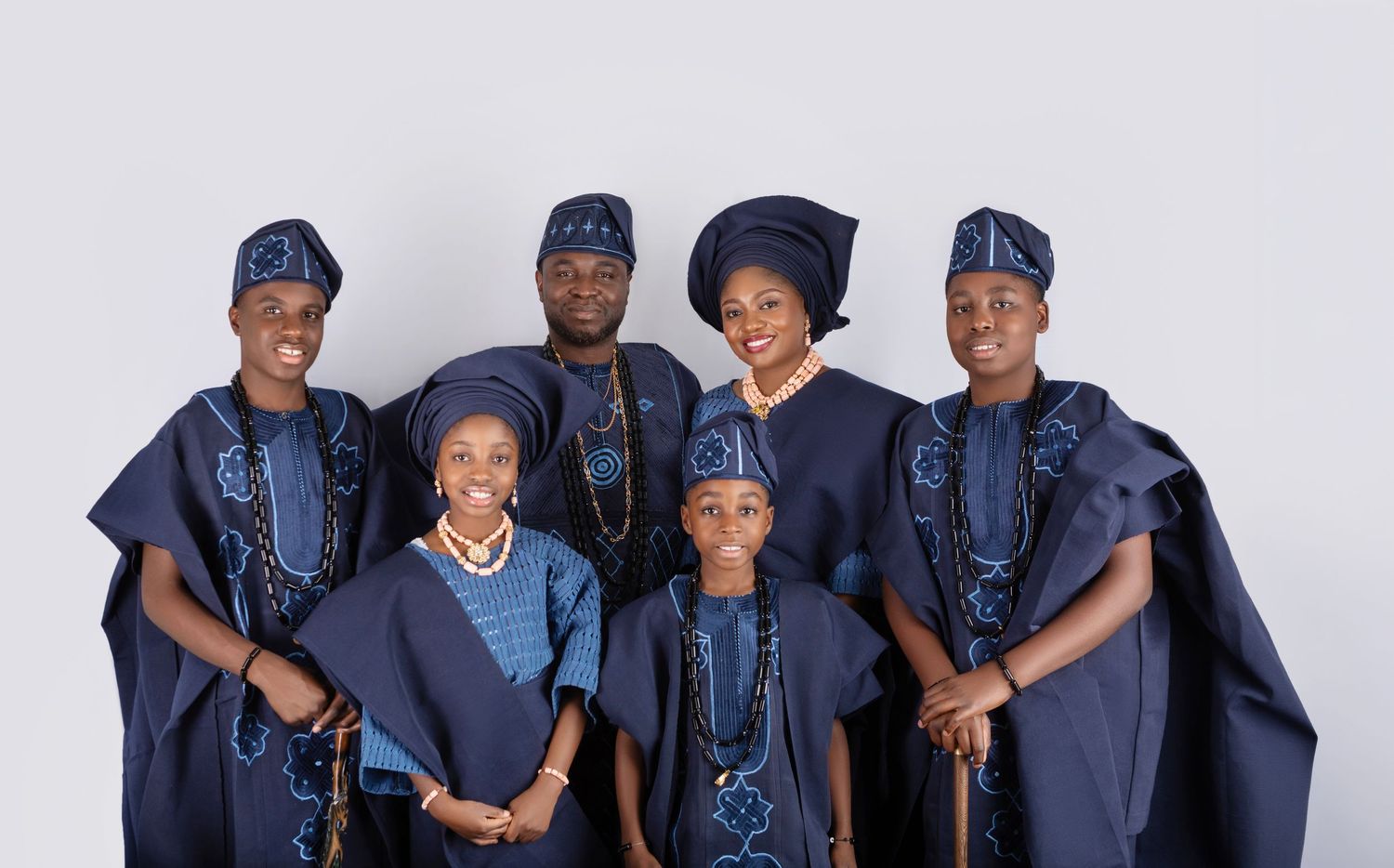 Nigerian family in matching navy blue traditional Yoruba attire with gele headwear posing for a formal portrait.