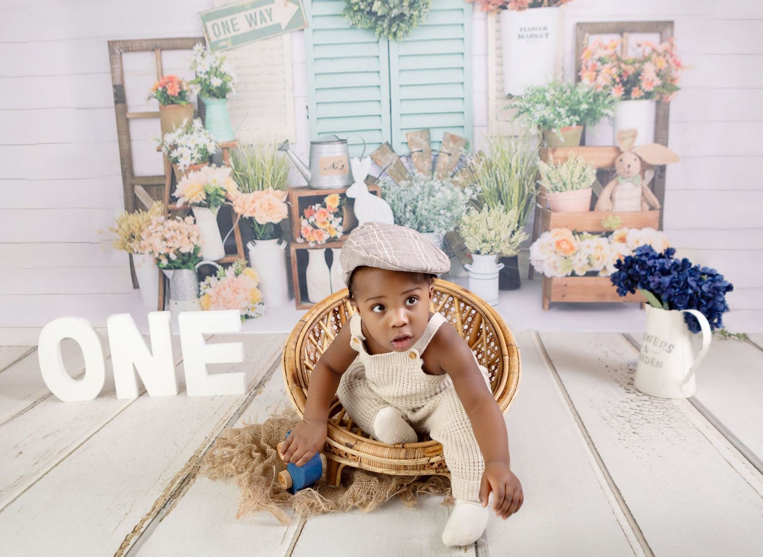 Baby's first birthday photo with floral backdrop, wicker basket, and ONE sign.
