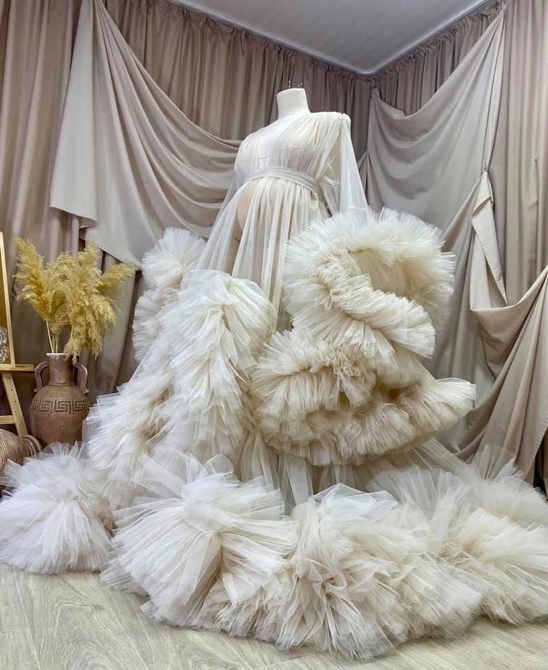 Ivory white dramatic ruffled tulle maternity gown with train on mannequin.
