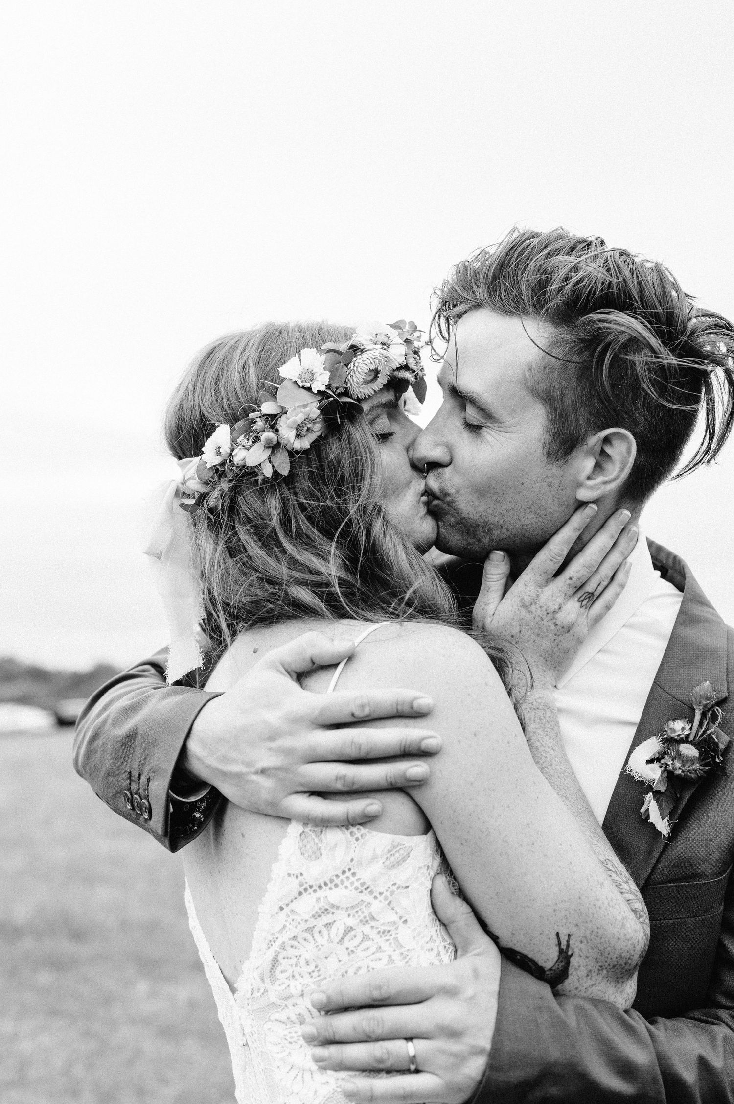 Black and white romantic portrait of couple embracing with flower crown detail.