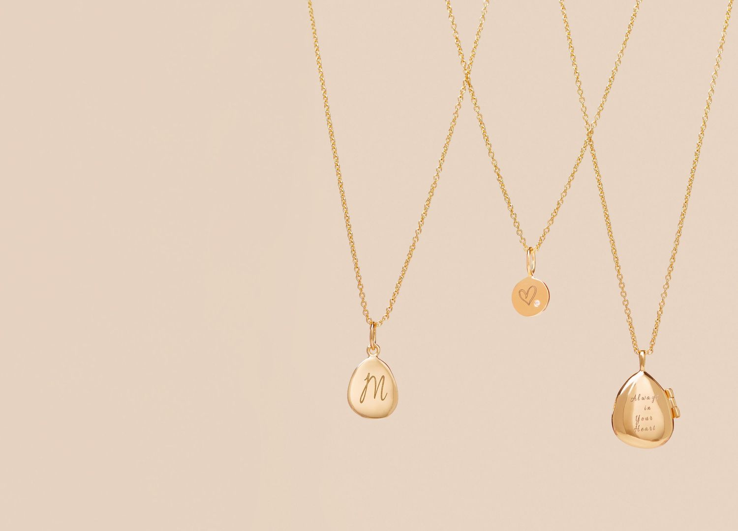 Three delicate gold necklaces with pendant charms displayed against a beige background.