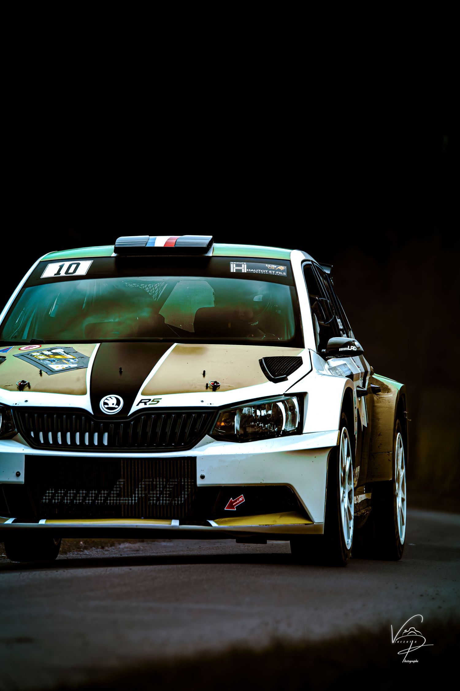 Modern race cars with sleek white bodywork and aggressive styling displayed in a dark studio setting.