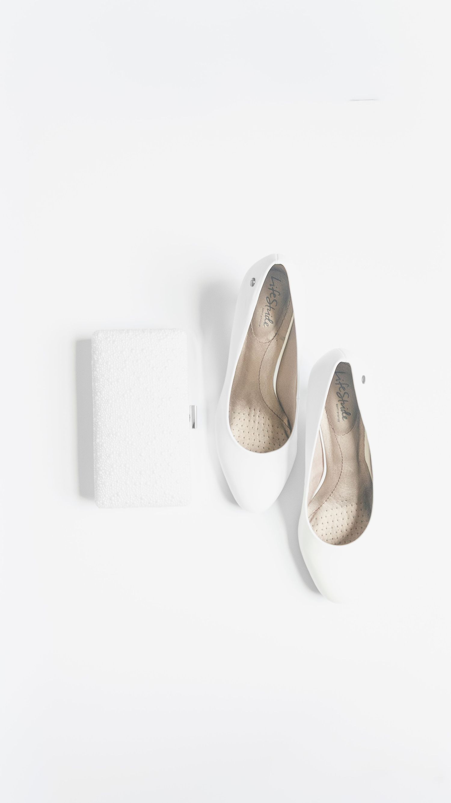 White ballet flats and matching textured clutch purse displayed on a white background.