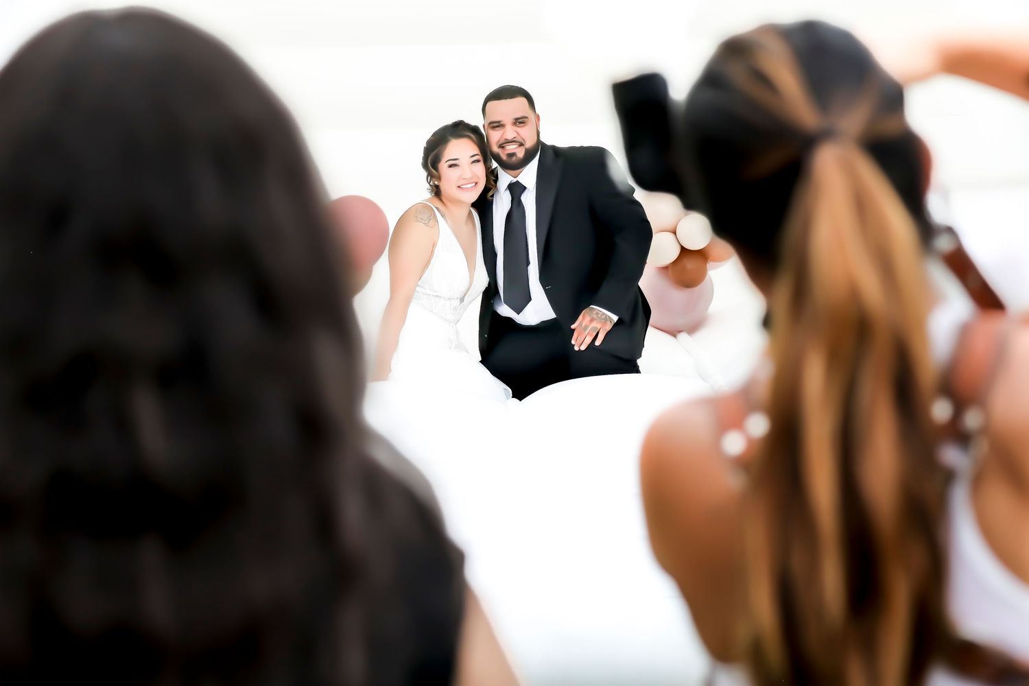 Photographer captures a couple posing on white backdrop during professional wedding photoshoot.