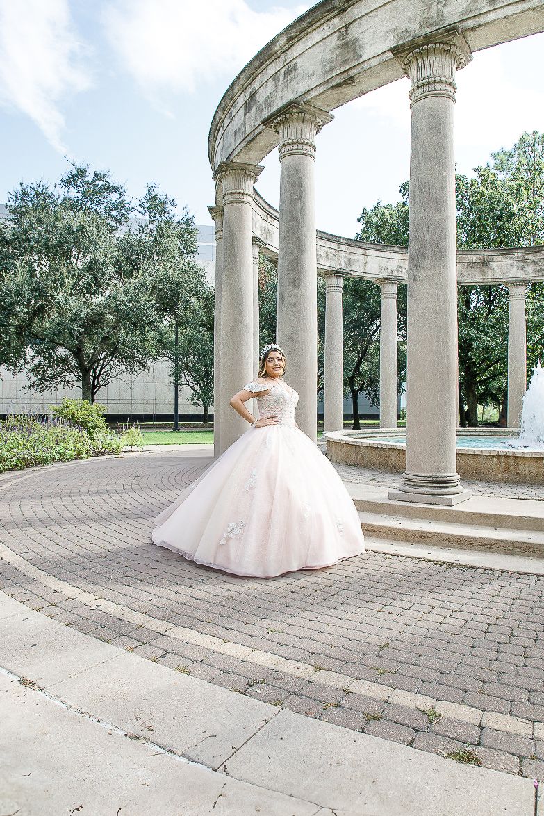 Elegant ballgown dress photographed in a classic columned colonnade with stone pillars and brick pavement.