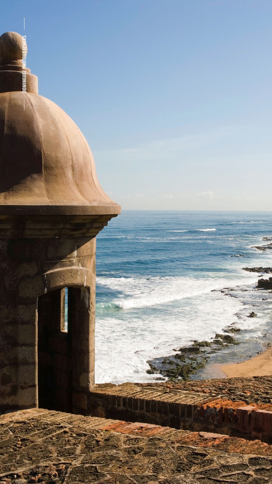 Ocean waves crash against rocky coastline with stone lookout tower overlooking the dramatic seascape.
