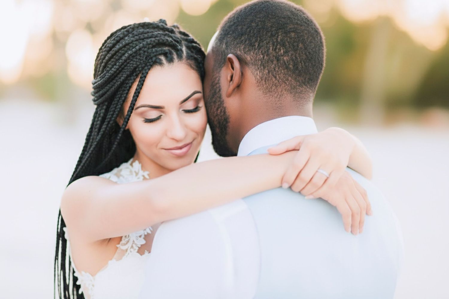A romantic couple embraces during a sunset photoshoot by a waterfront in soft golden light.