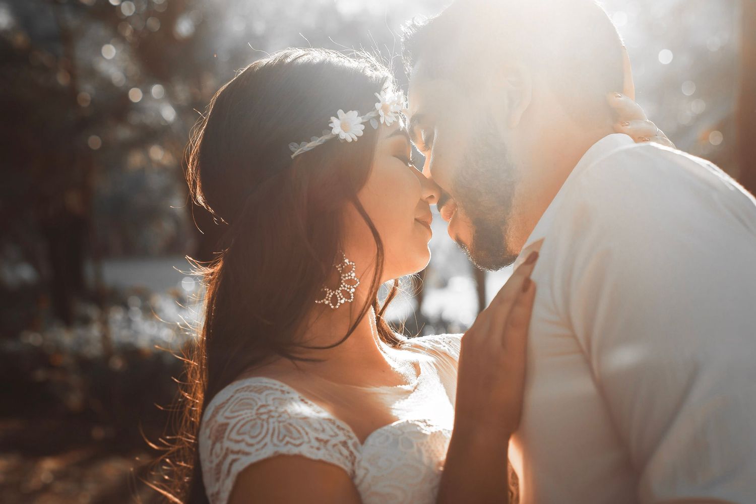 A romantic golden sunset silhouettes a couple in love sharing an intimate moment.