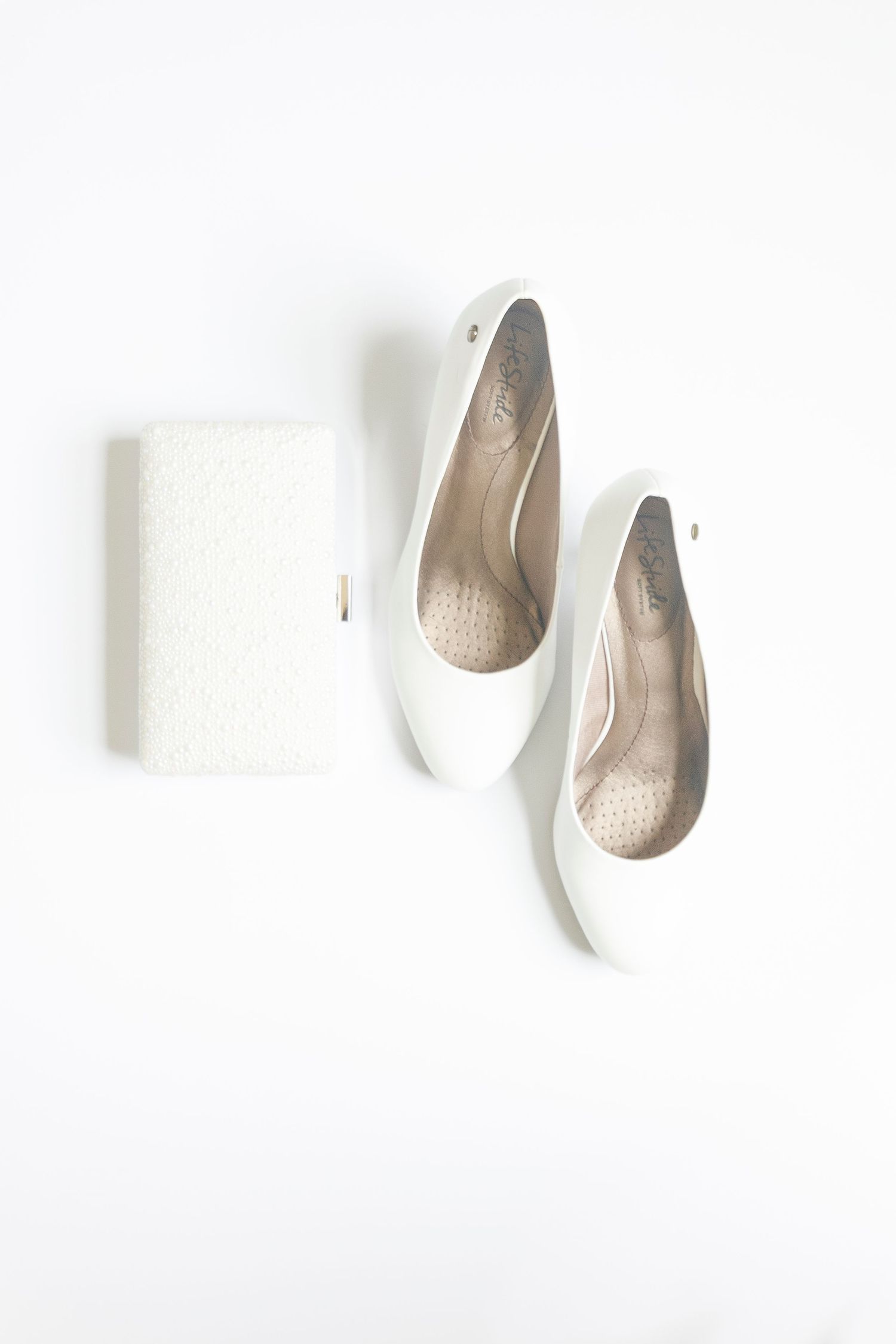 White ballet flats and matching glitter clutch purse arranged on a clean white background.