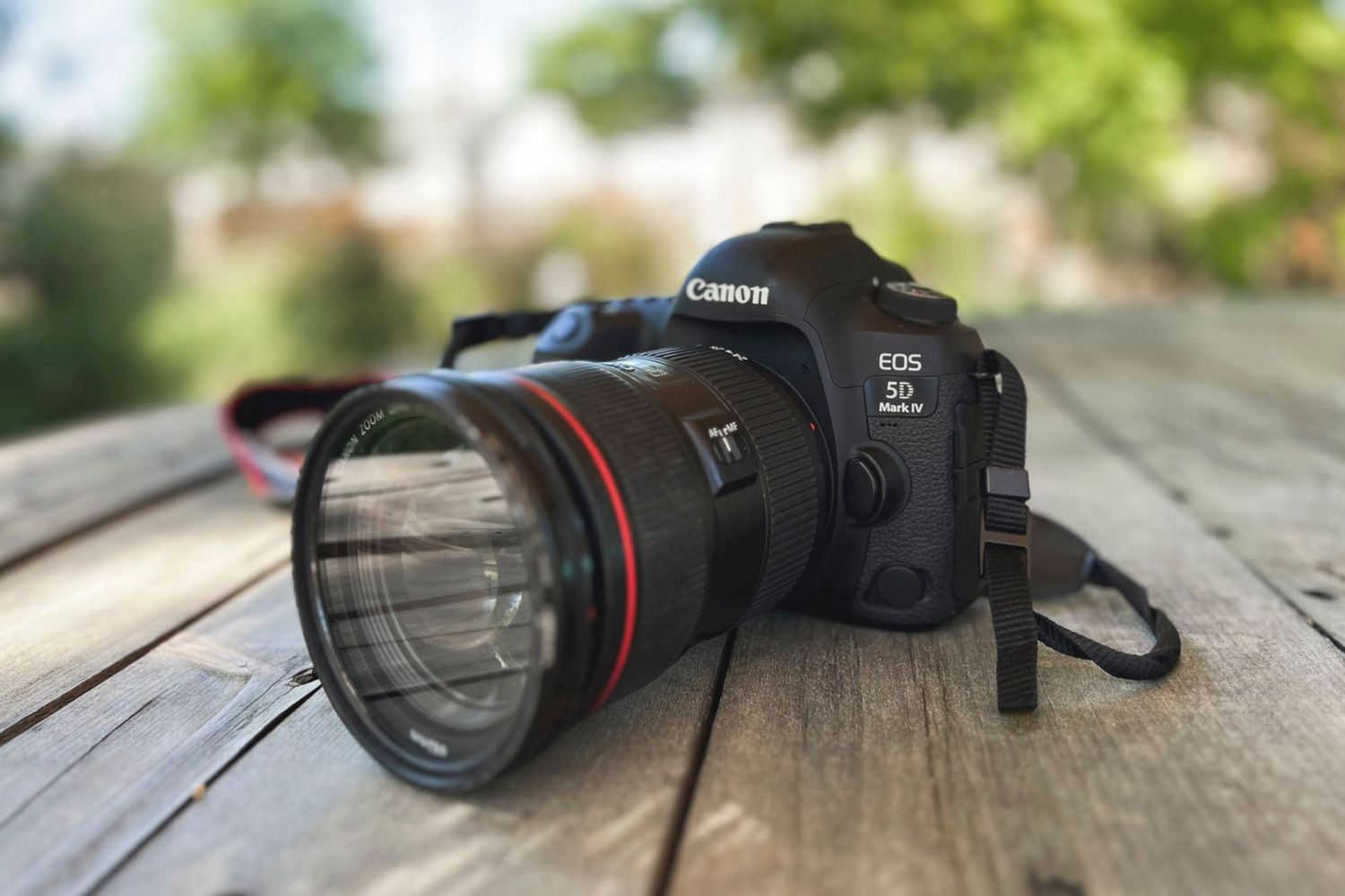 Canon DSLR camera sitting on a wooden surface with shallow depth of field focus effect.