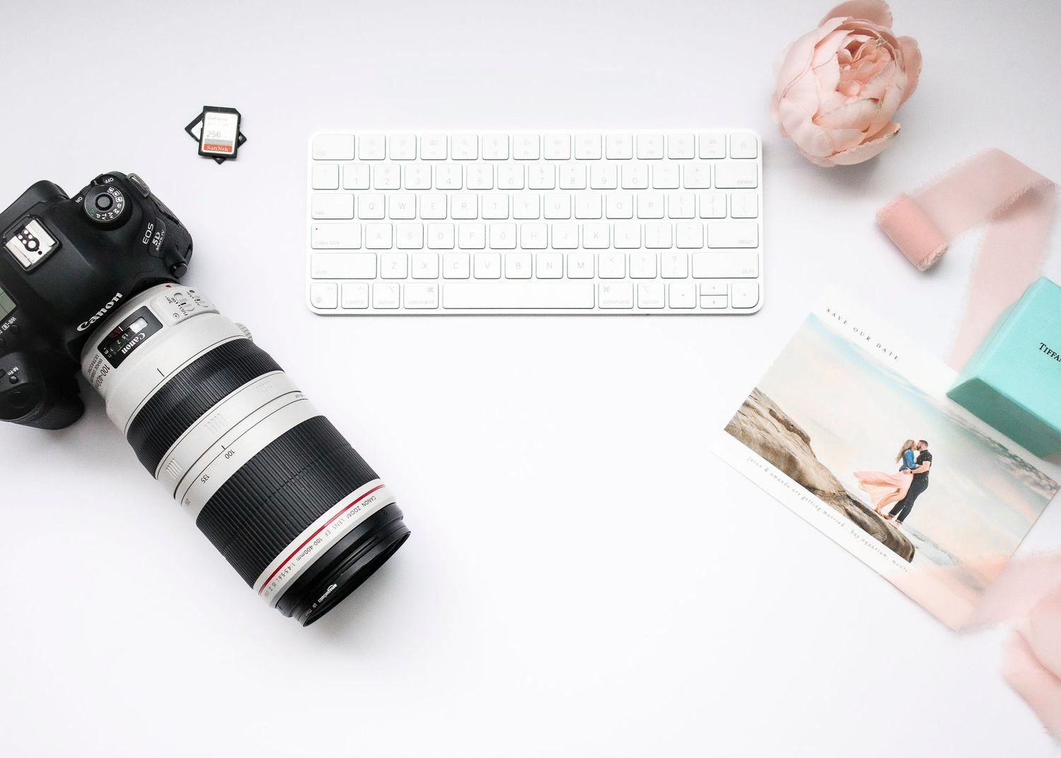Soft pink and white minimalist flat lay photography composition with delicate papers and office supplies.