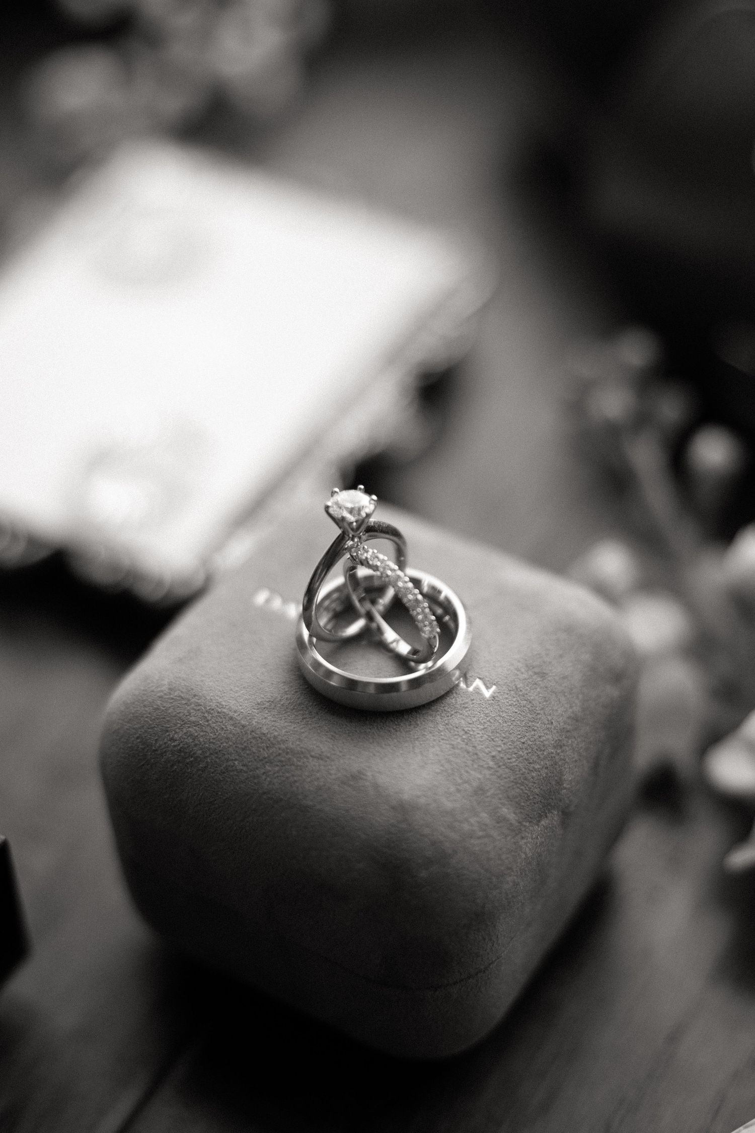 A series of black and white photographs showing an engagement ring from different angles on a soft surface.
