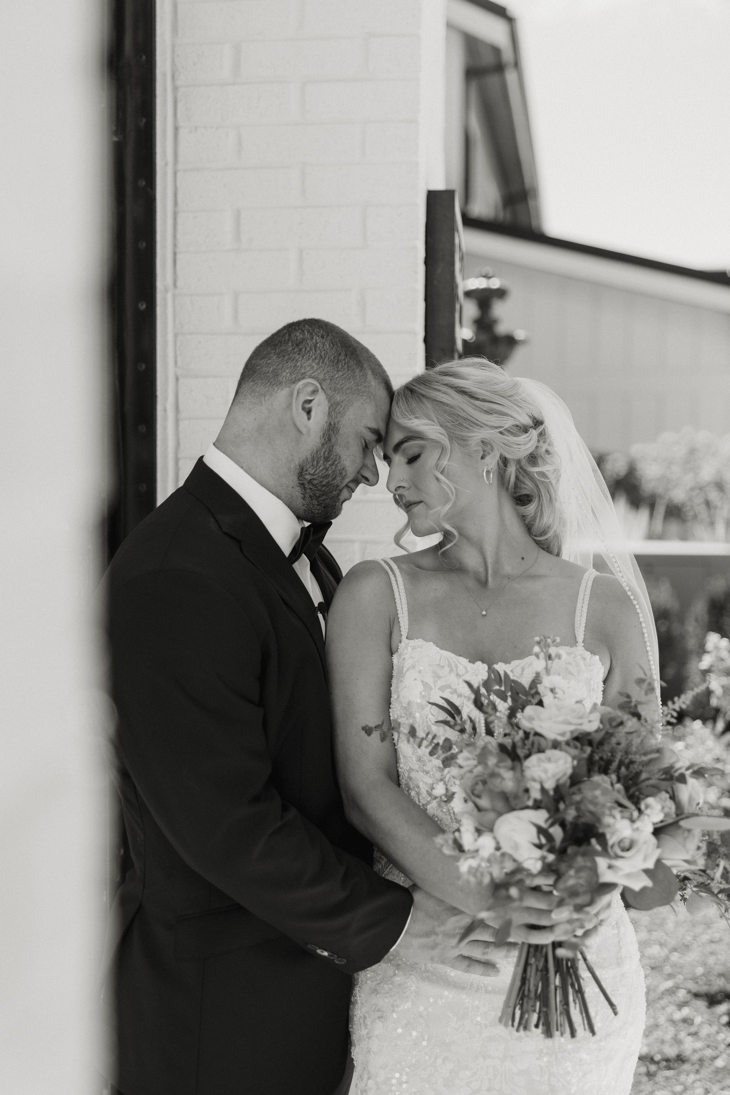A romantic black and white wedding photo sequence shows a couple sharing tender moments and kisses with beautiful floral bouquet.