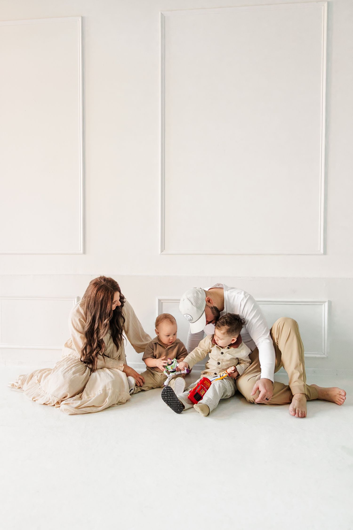 Family lying down together on white floor during intimate photo session.