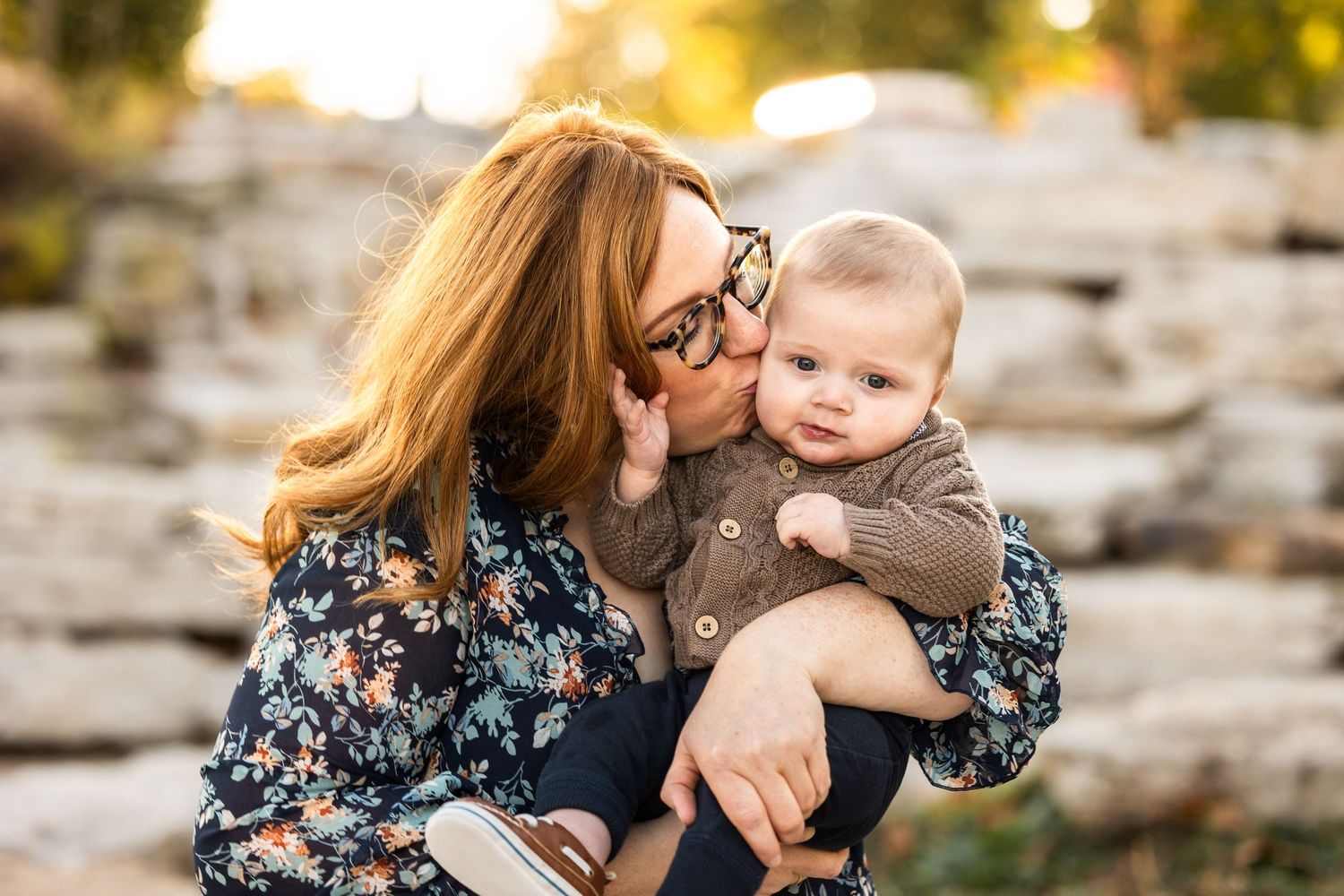 A tender moment captured between parent and child against a rocky outdoor backdrop.
