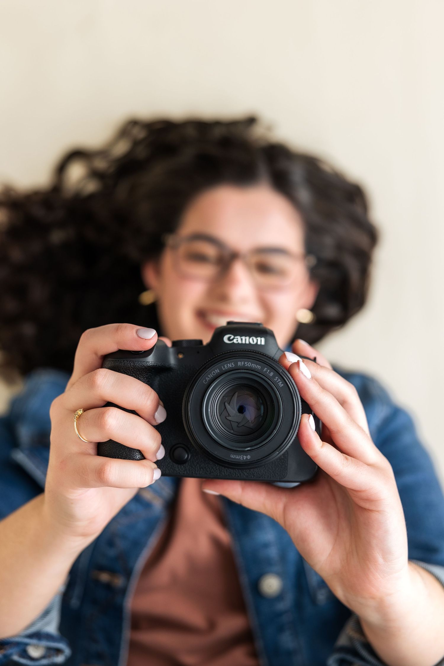 Close up shot of hands holding a Canon camera against a light background.