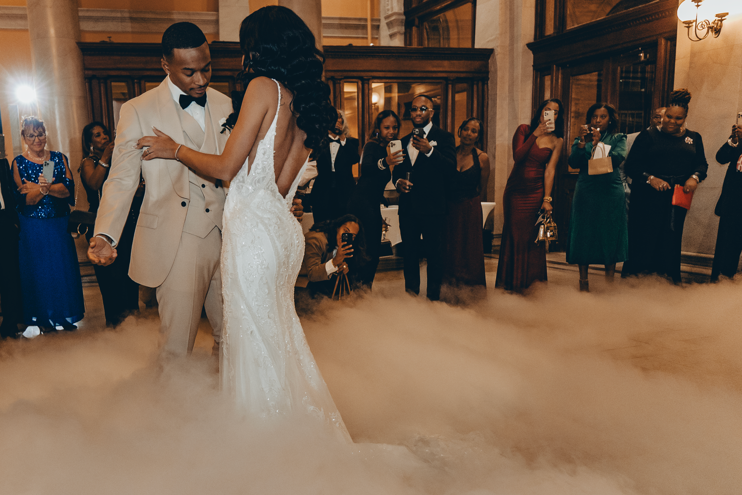 A couple shares their first dance on a fog-covered dance floor at their elegant wedding reception.