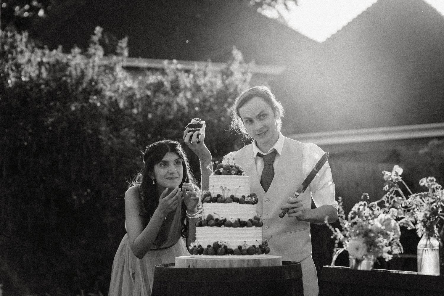 Black and white wedding photos showing reception moments with cake cutting, dancing, and floral decorations.