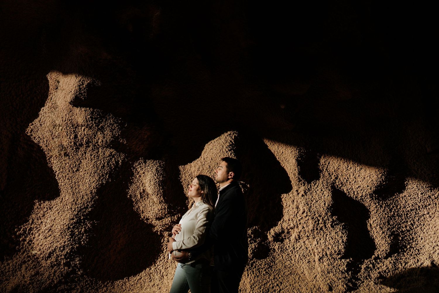 A close-up view of dark brown soil or earth texture with shadows and highlights creating depth and detail.