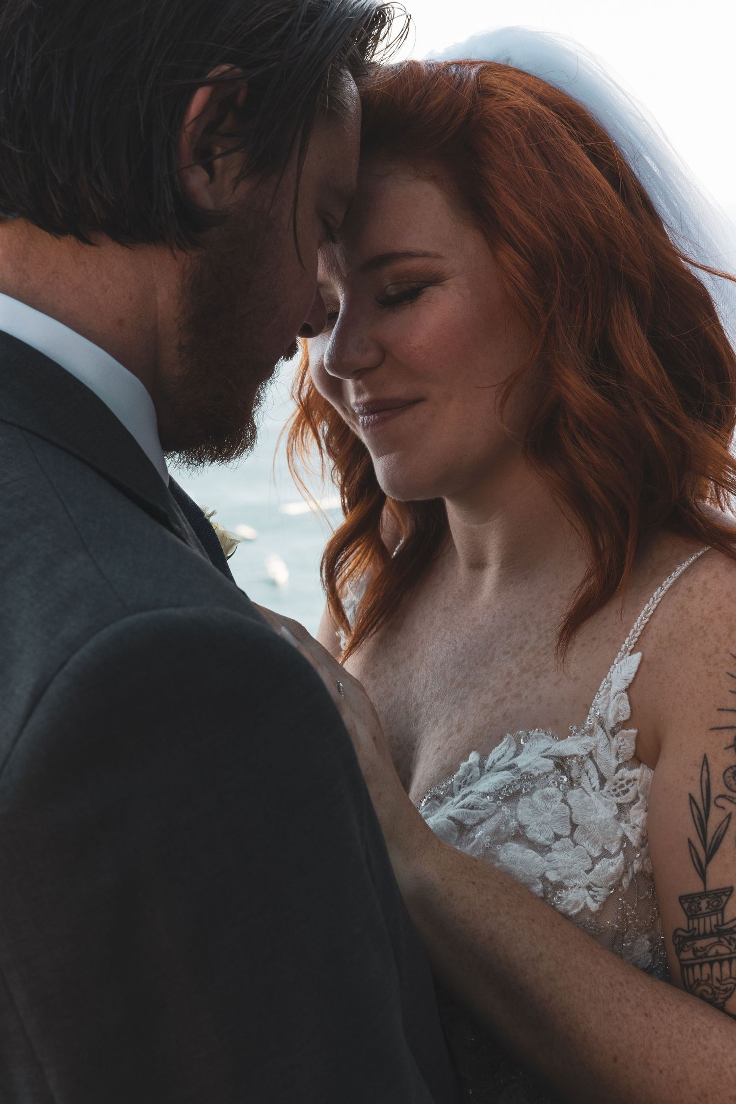 A romantic wedding couple embraces in a series of intimate close-up shots showing lace dress details and tender moments.