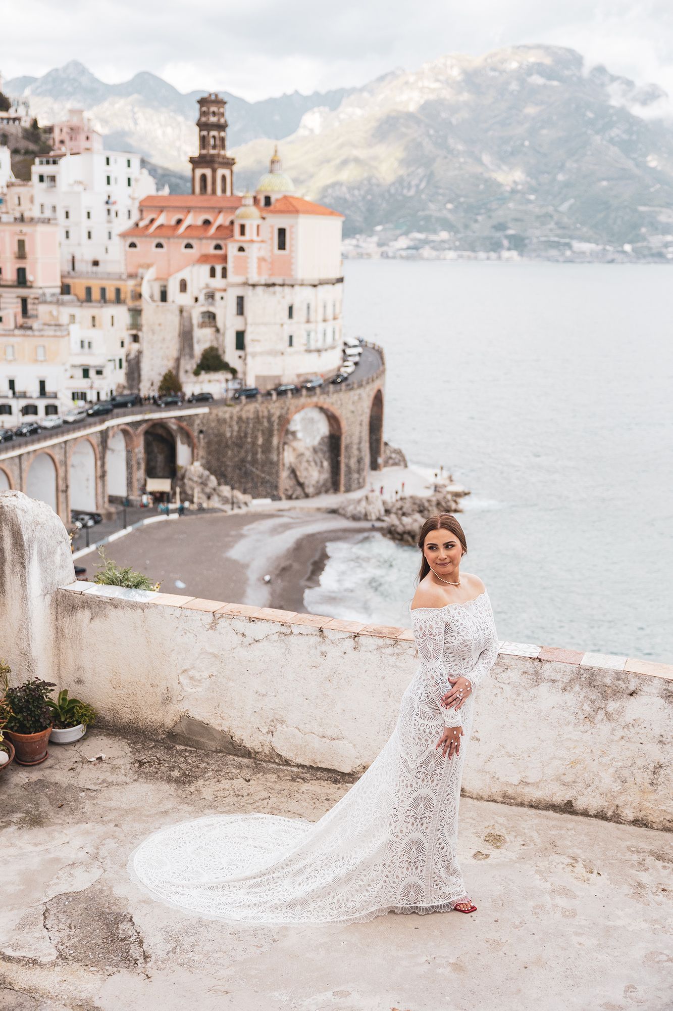 Scenic view of Atrani village on Italy's Amalfi Coast with historic church tower and Mediterranean coastline in background.