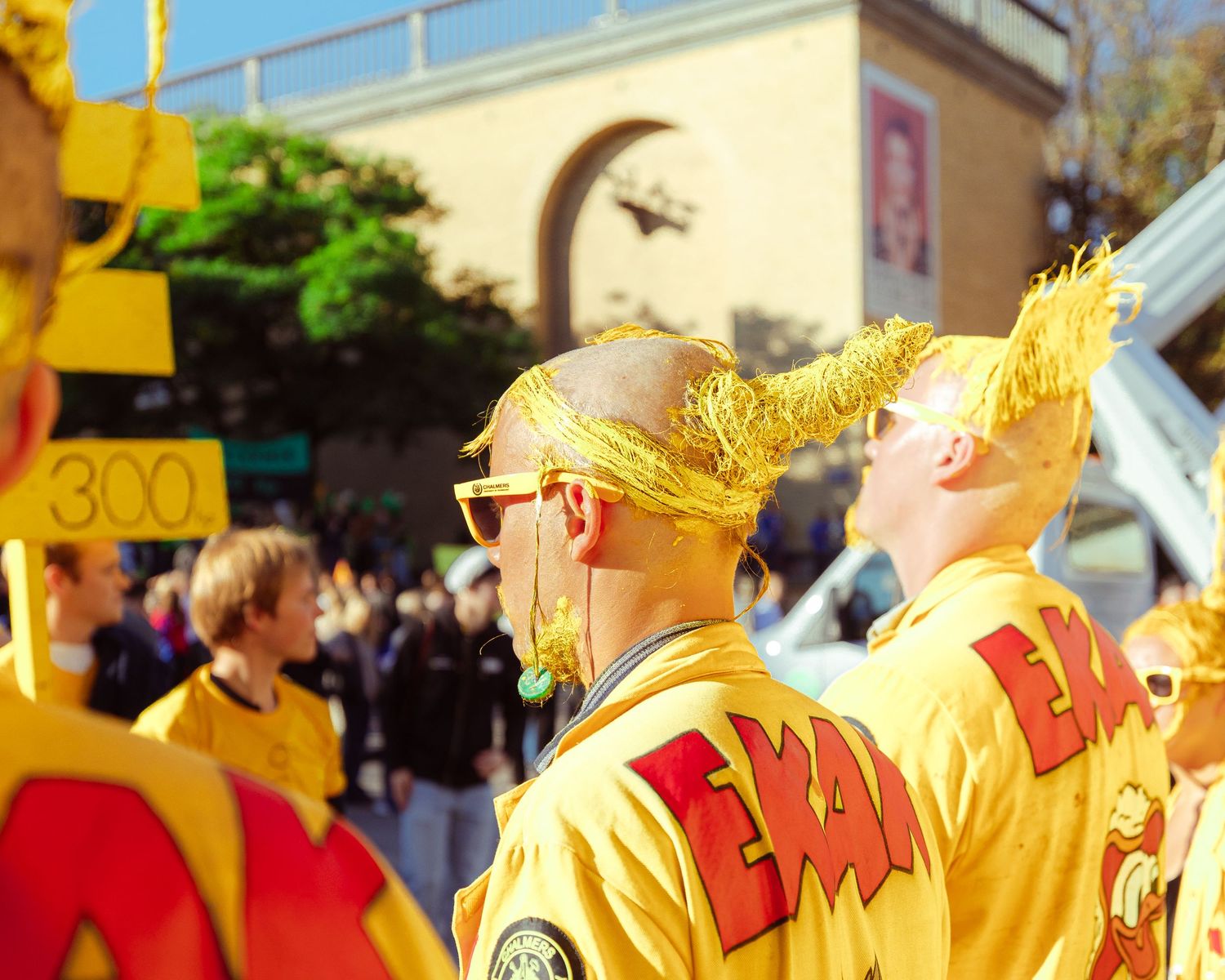Two people in yellow costumes with wild hair at a colorful street parade event.