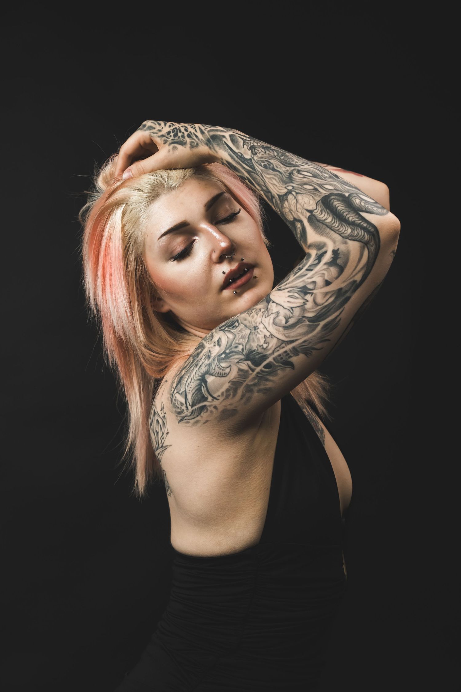 Moody studio portrait with dramatic lighting, deep shadows, and rich contrast, creating an intimate, artistic, and striking image.