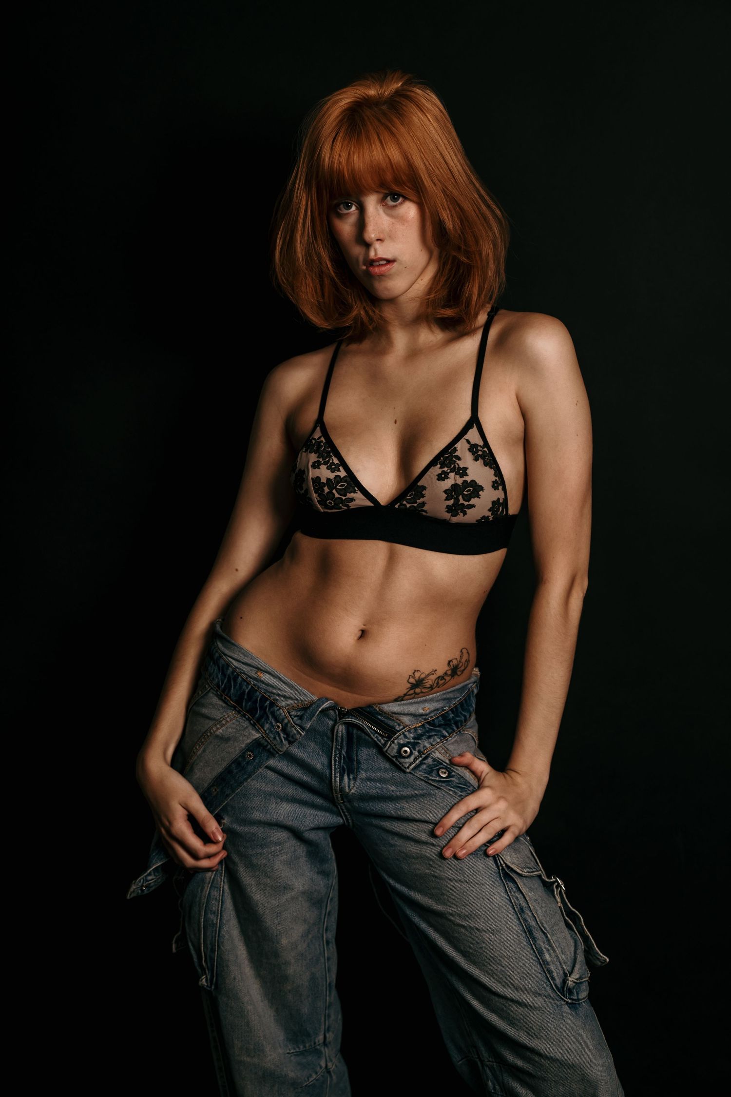 Moody studio portrait with dramatic lighting, deep shadows, and rich contrast, creating an intimate, artistic, and striking image.