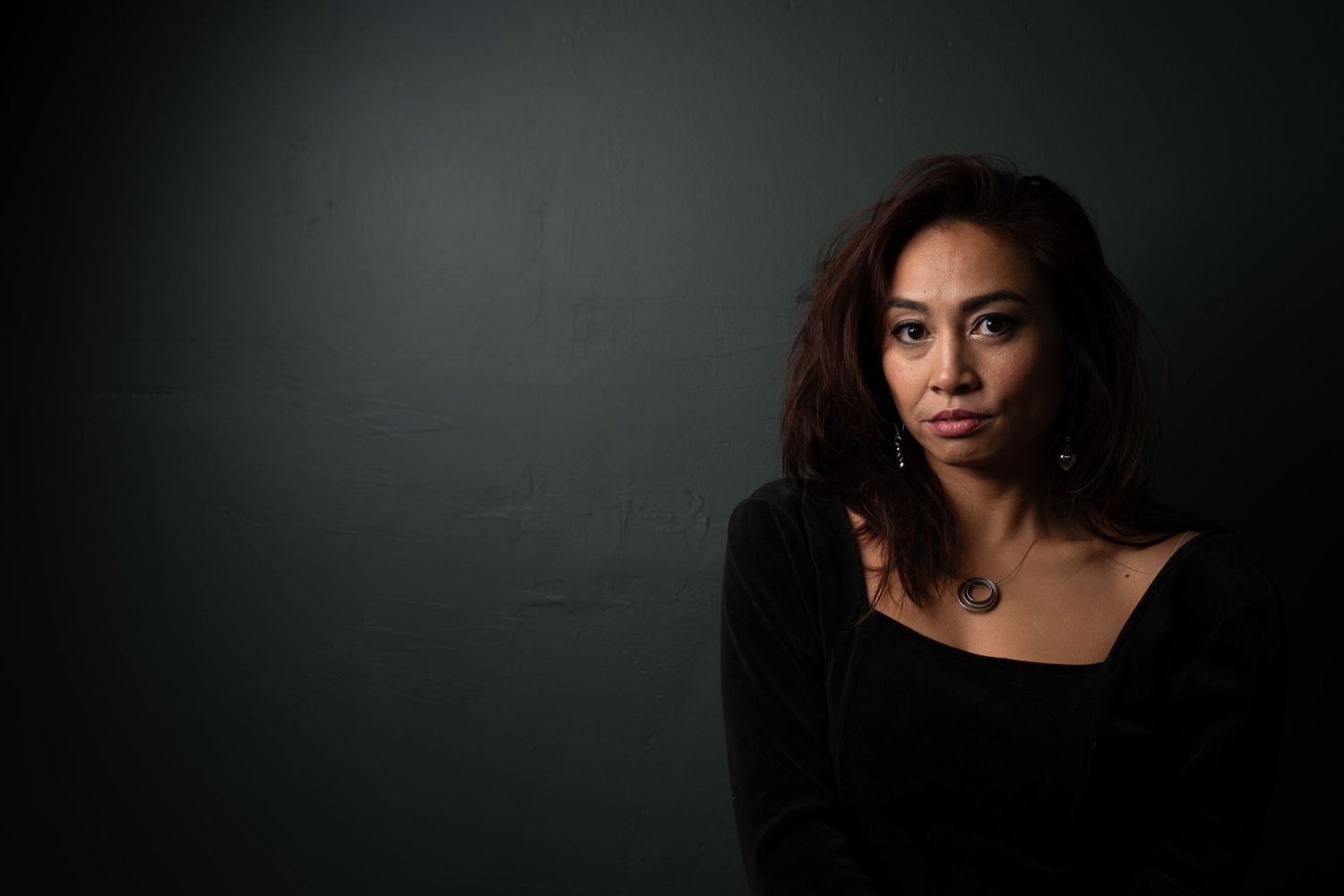 Moody studio portrait with dramatic lighting, deep shadows, and rich contrast, creating an intimate, artistic, and striking image.