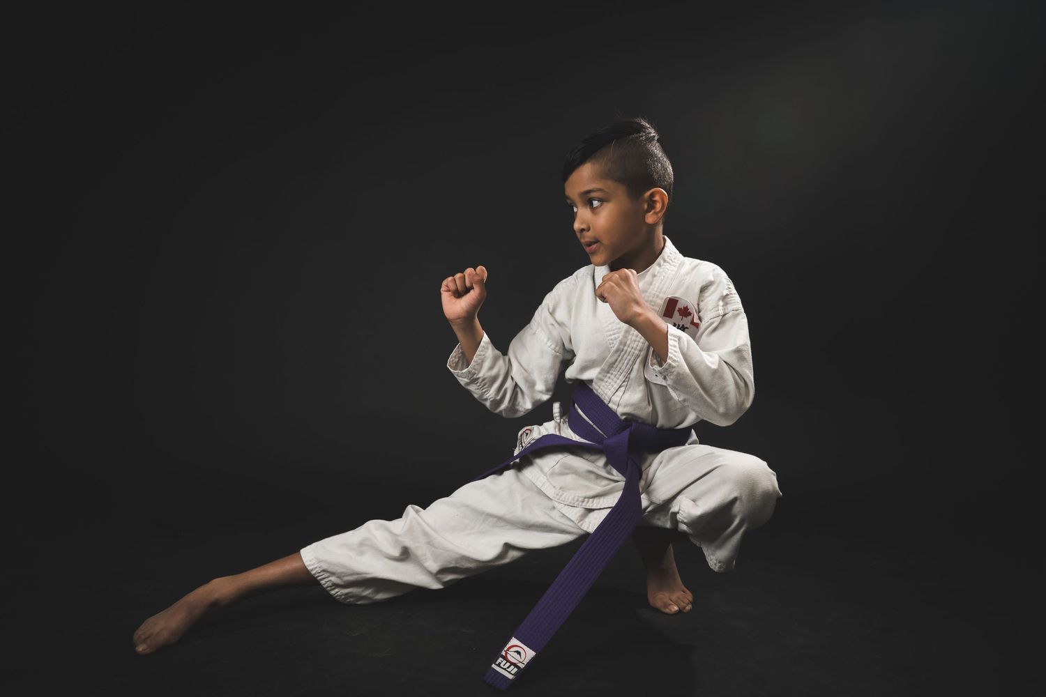 Young karate kid posing confidently in a studio portrait, wearing a karate uniform with dramatic lighting