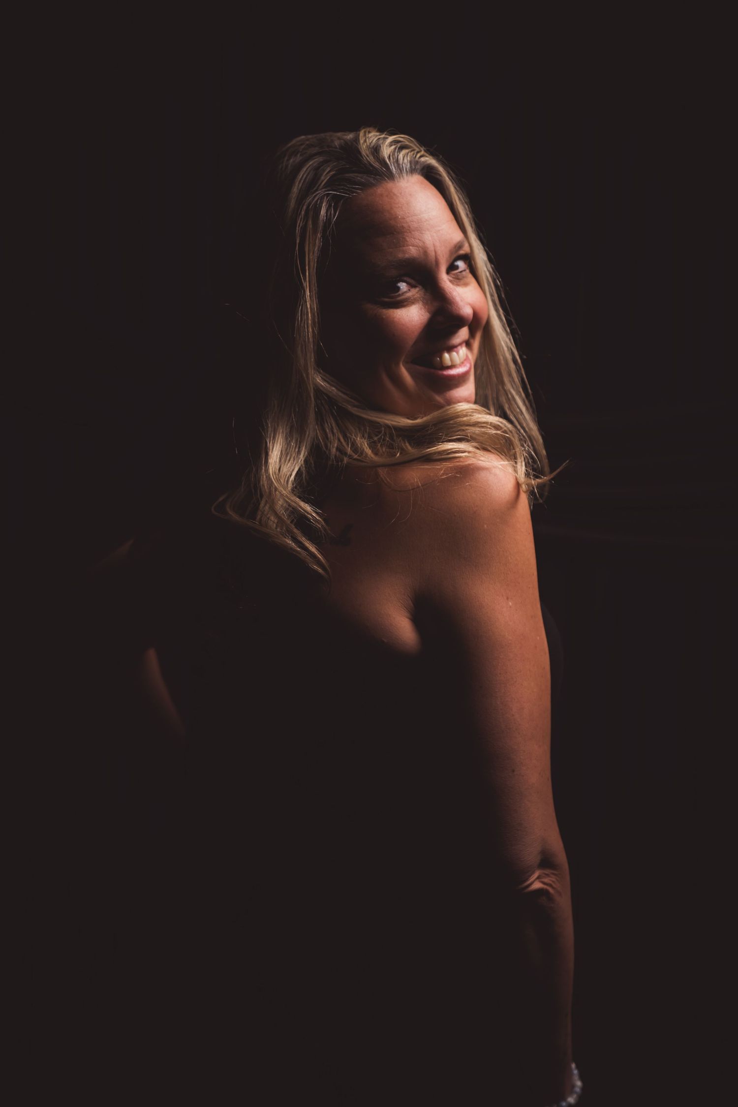 Moody studio portrait with dramatic lighting, deep shadows, and rich contrast, creating an intimate, artistic, and striking image.