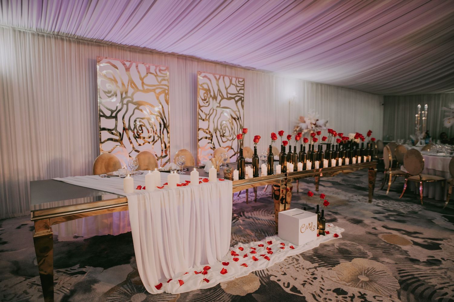 Wedding reception head table with white draping, rose artwork panels, and red rose centerpieces. Epicu Fotograf Drobeta-Turnu Severin