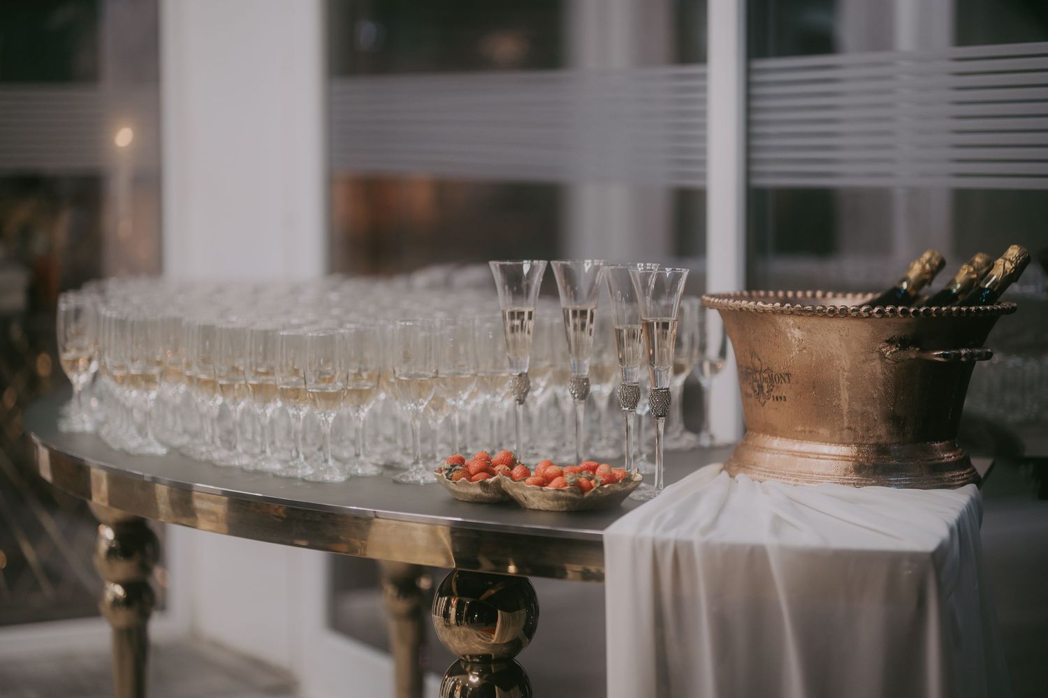 Rows of champagne flutes arranged on draped table with gold champagne bucket at wedding. Epicu Fotograf Drobeta-Turnu Severin