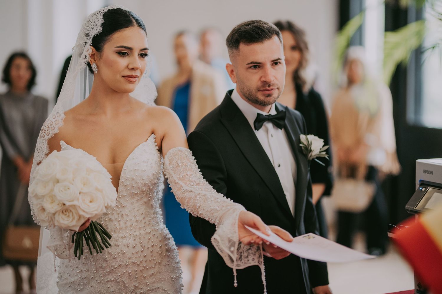 Bride in beaded gown and groom in tuxedo during wedding ceremony reading vows.