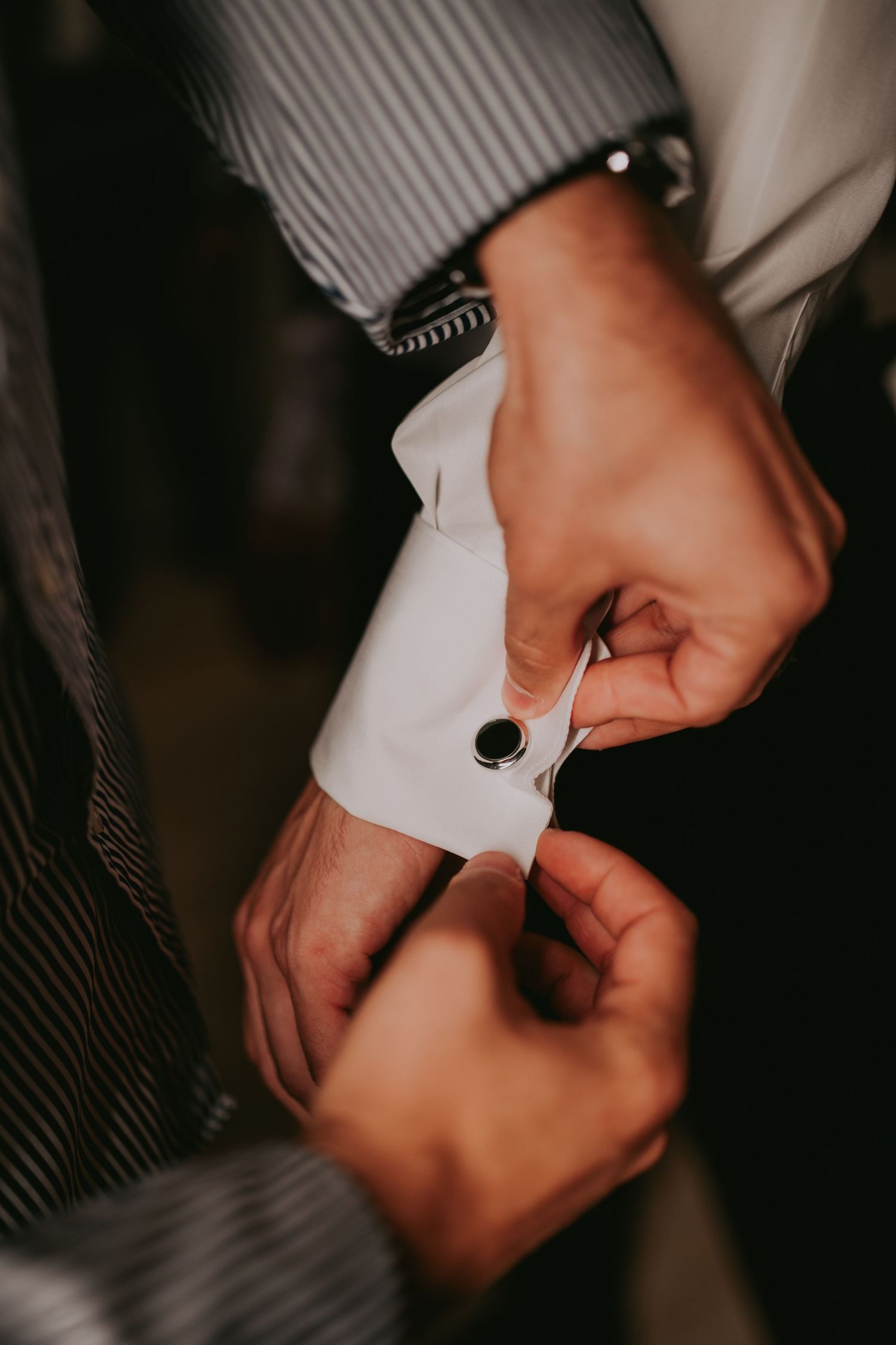 Close-up of hands fastening a black cufflink on a white dress shirt sleeve. Epicu Fotograf Drobeta-Turnu Severin
