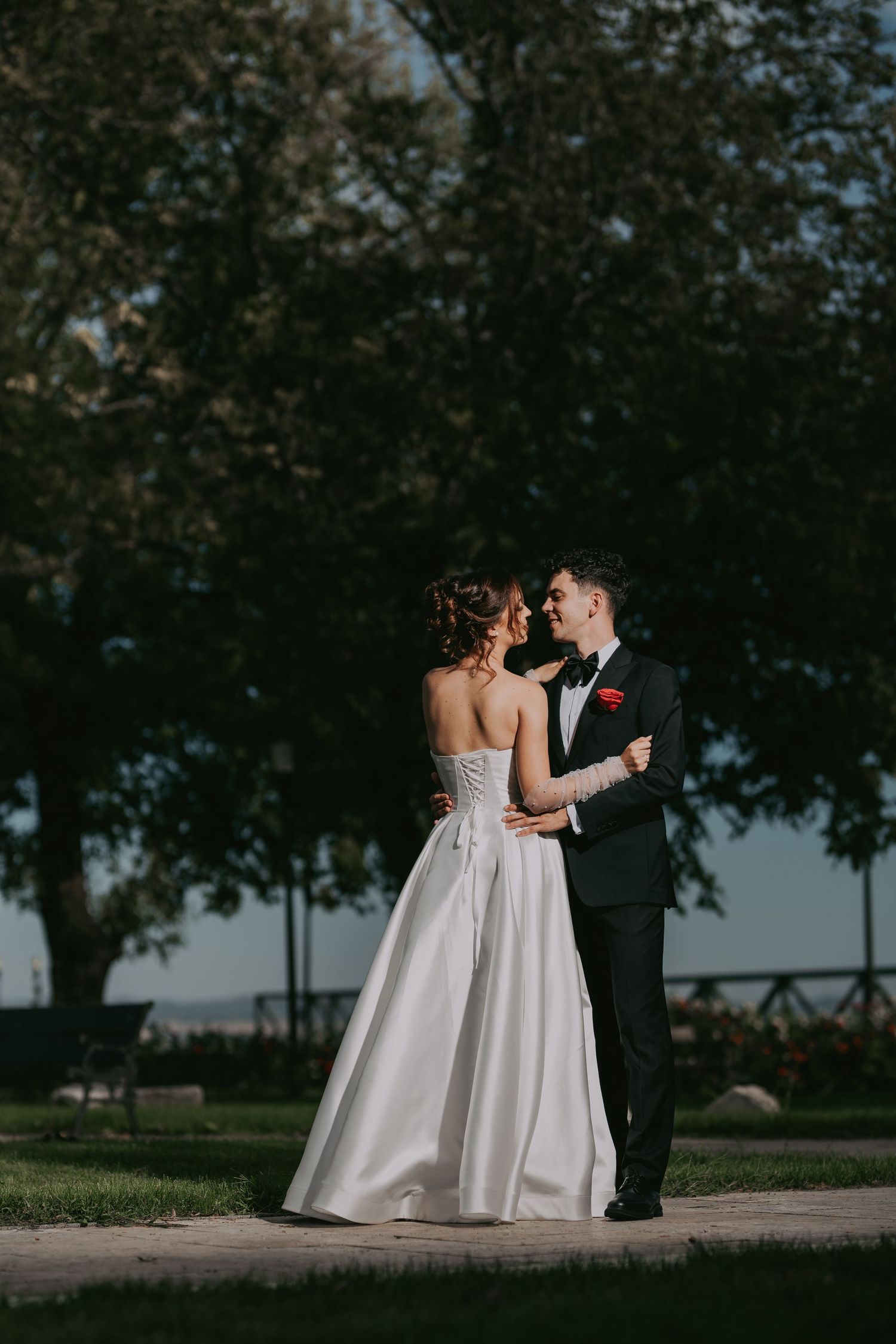 Bride and groom embracing in a lush green park with trees in the background. Epicu Fotograf Drobeta-Turnu Severin