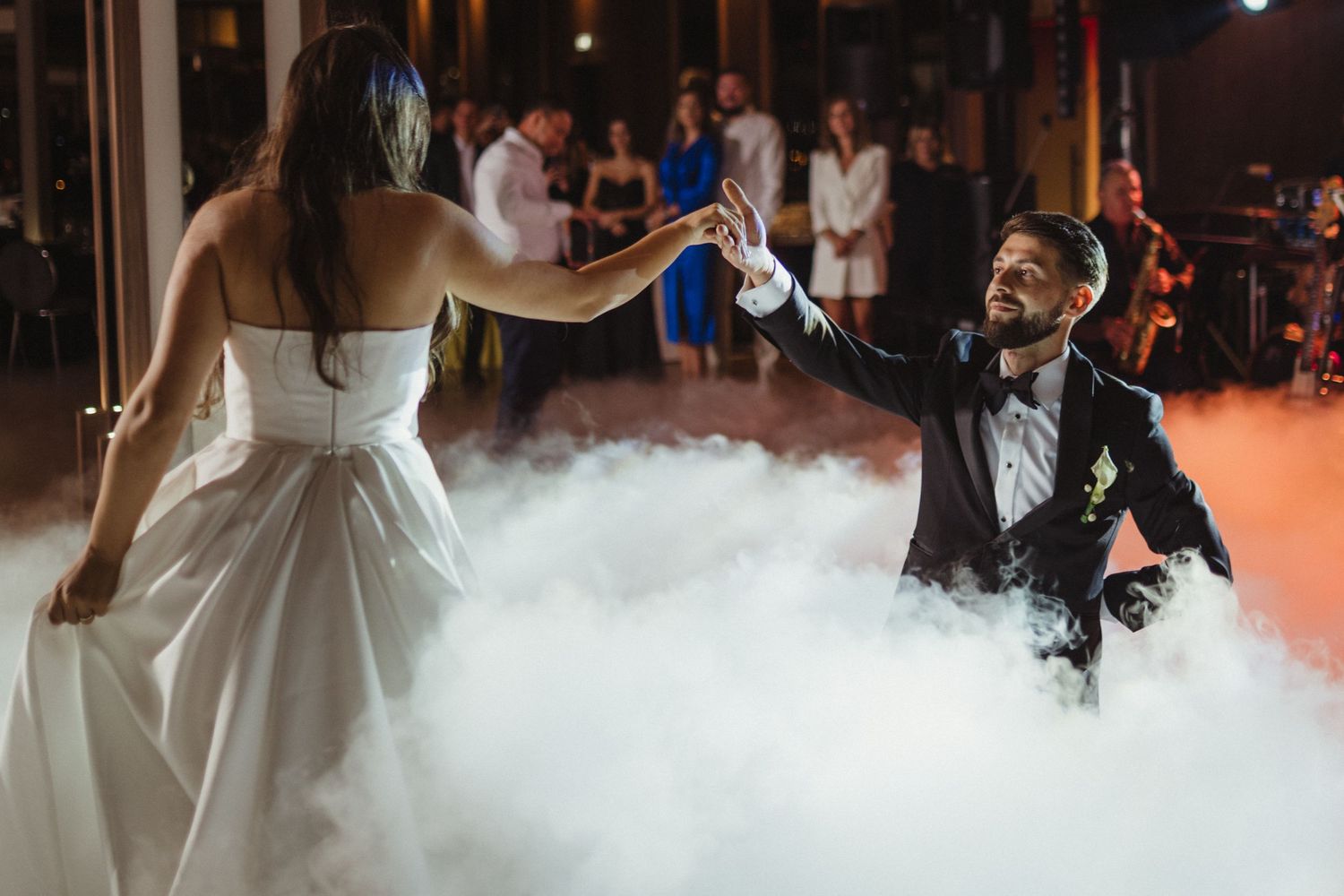 Bride and groom sharing first dance surrounded by dramatic fog at wedding reception.
