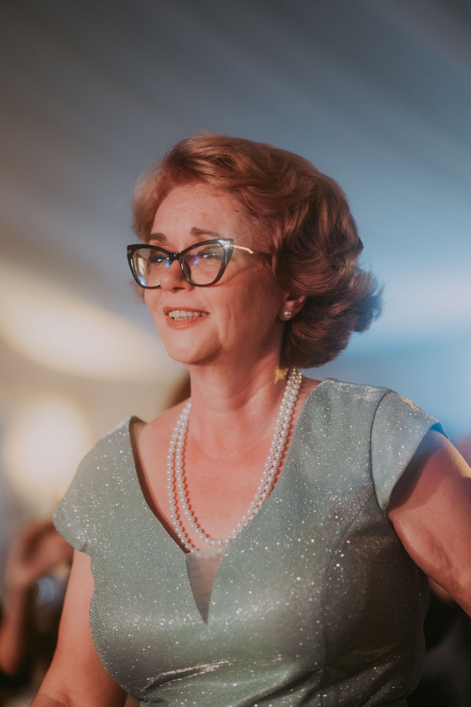 Elegant older woman in silver dress and pearl necklace smiling at a wedding reception. Epicu Fotograf Drobeta-Turnu Severin