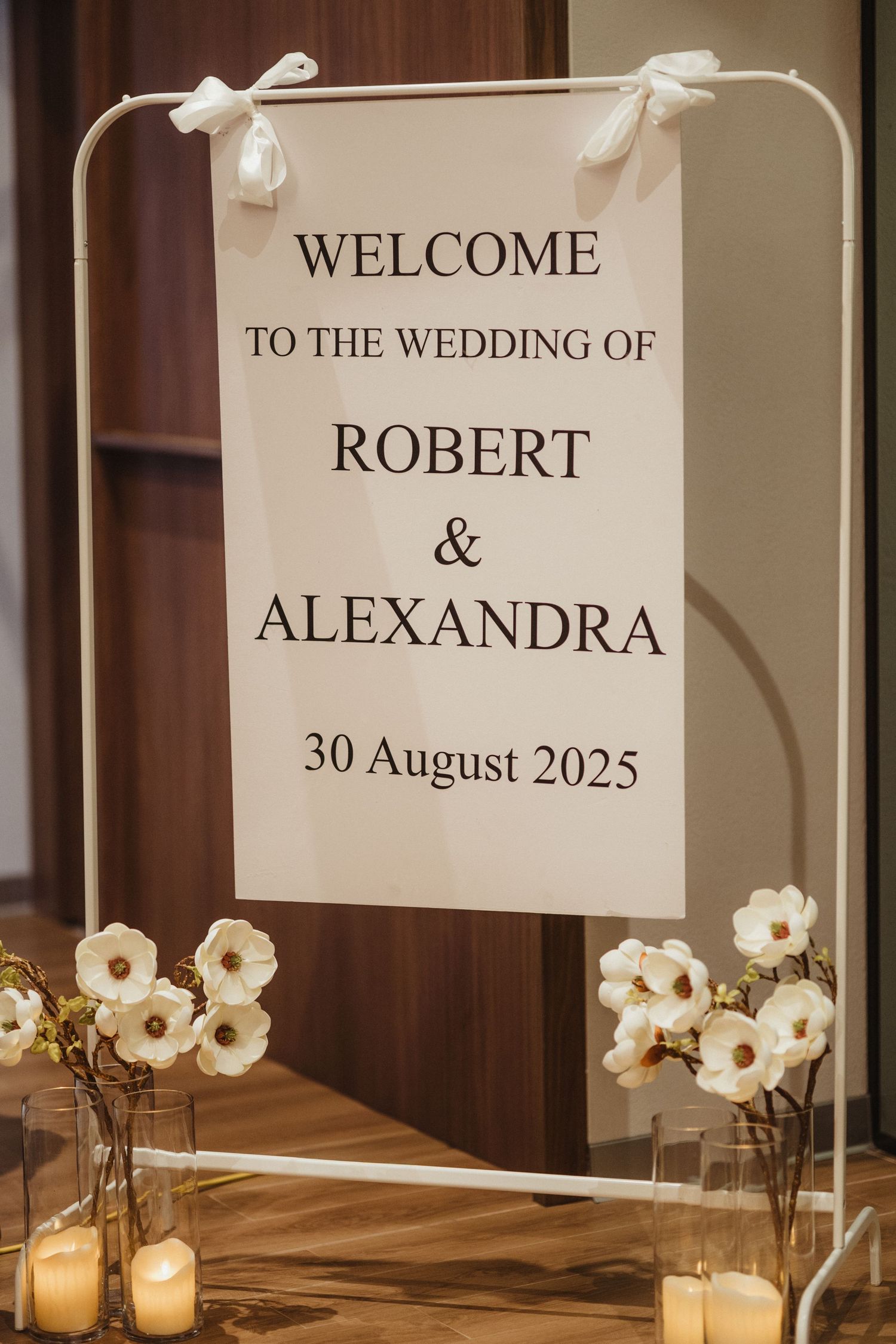 Elegant wedding welcome sign for Robert and Alexandra, August 30 2025, with white flowers.