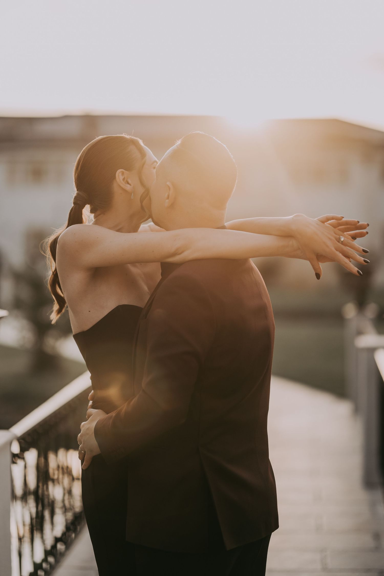 Romantic couple sharing a kiss at golden hour, woman in black dress embracing man in dark suit. Epicu Fotograf Drobeta-Turnu Severin
